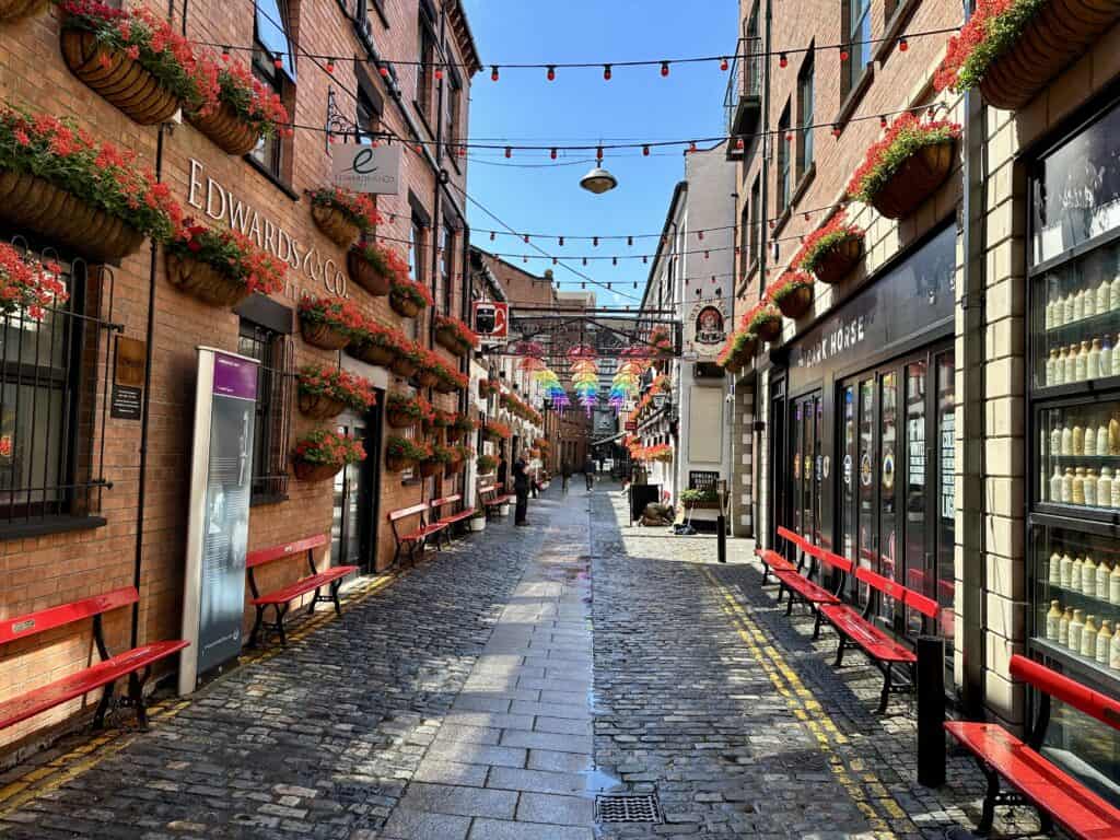 Festive street in Belfast with colorful streamers across the narrow street lined with shops and restaurants