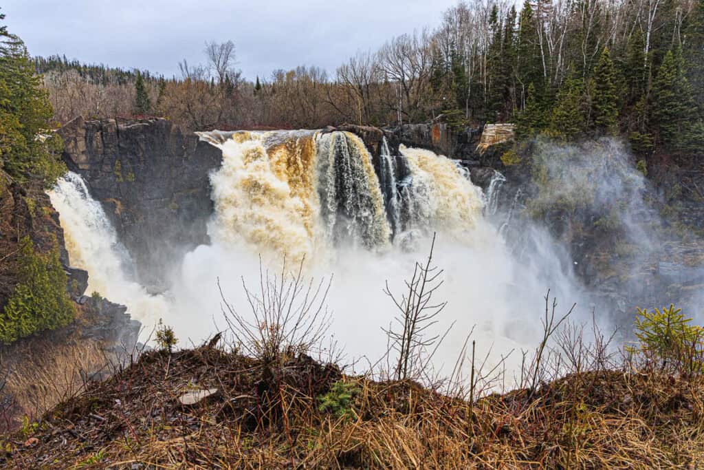 Enormous waterfall with at least a dozen different sections coming down and mist rising up all around like heavy smoke.