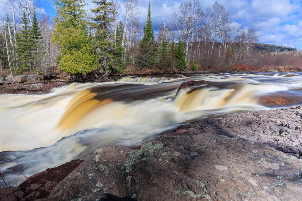 A smaller but beautiful set of waterfalls, colorfully flowing with root beer colored water in places.