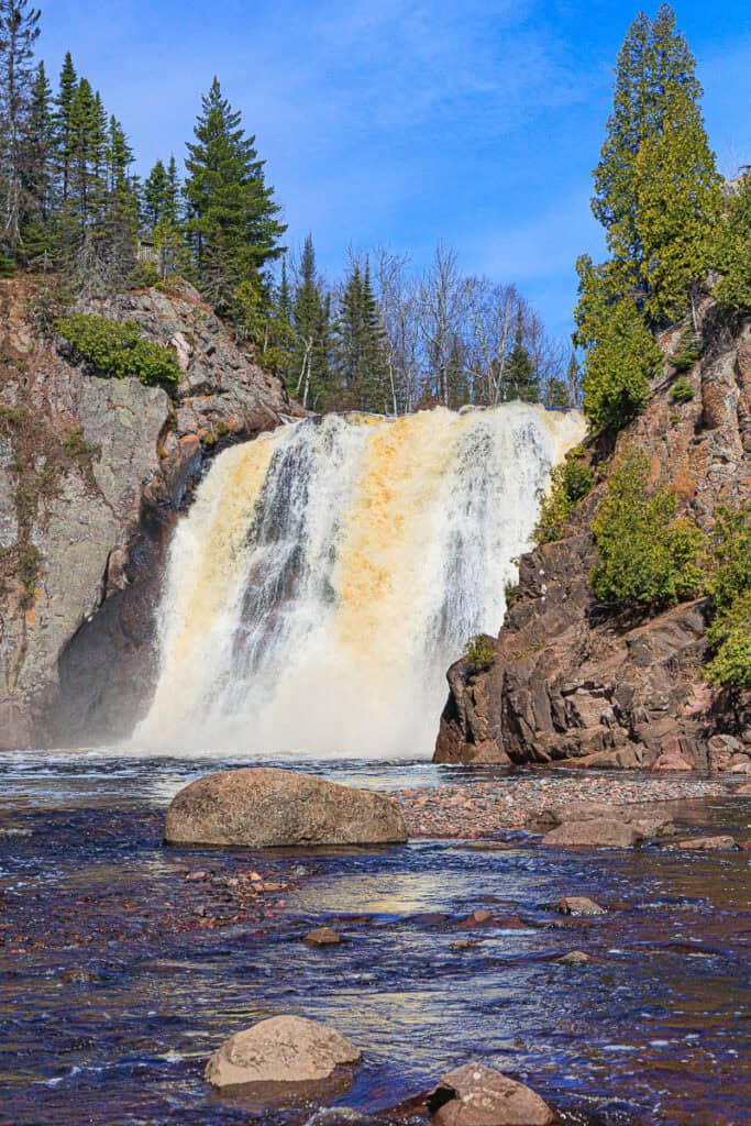 Wide waterfall pouring into a rocky pool below.