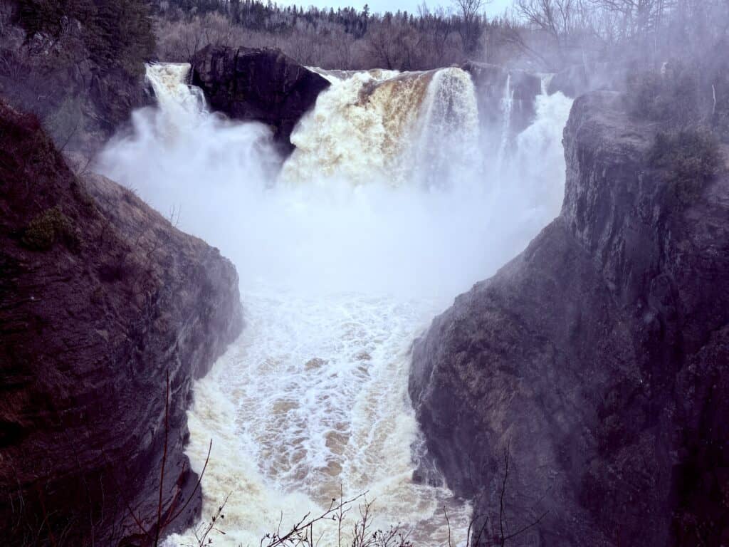A further away view of the falls, showing the river raging down the canyon after the falls.