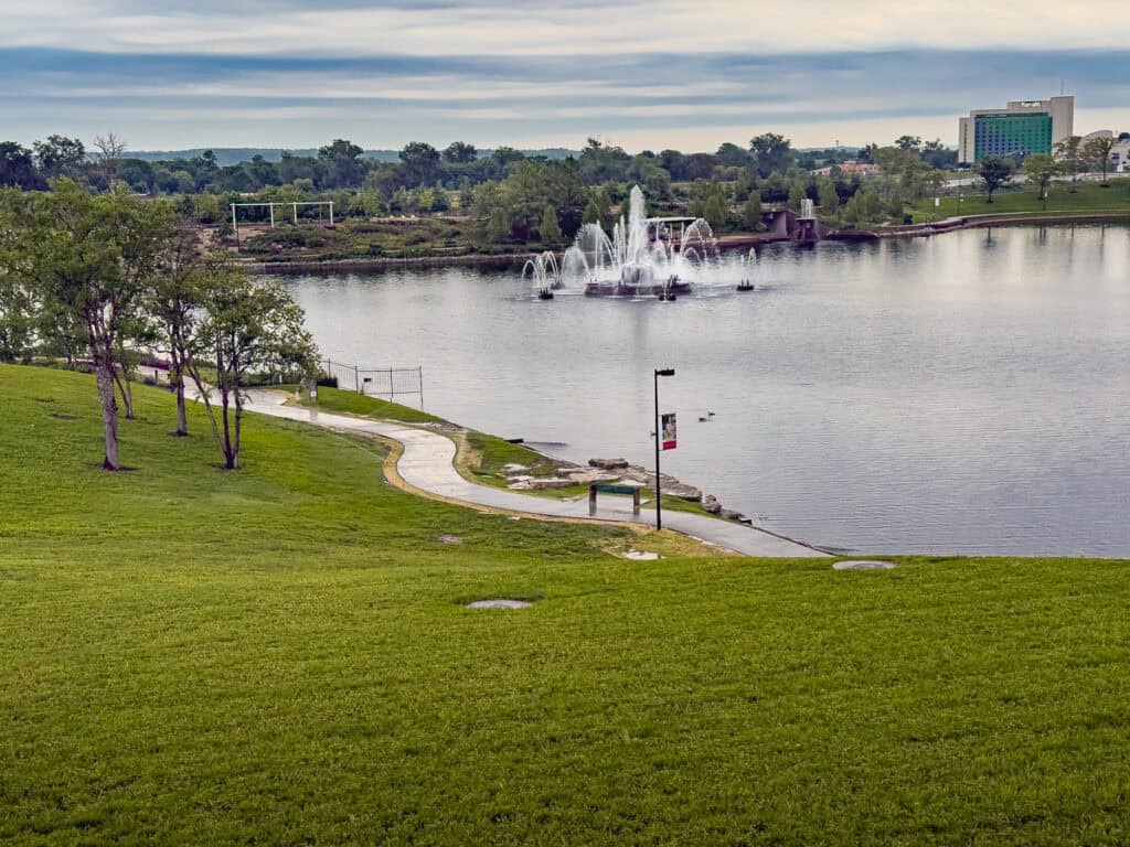 A lake with a fountain in the middle, and a trail around it.