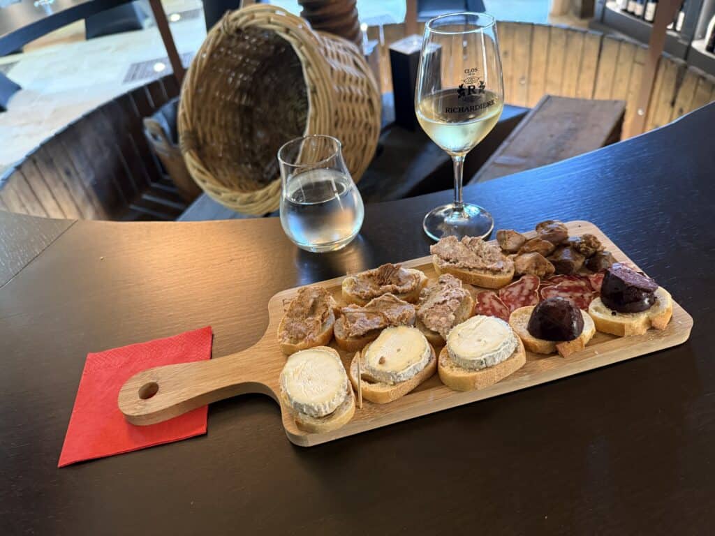 Food & Wine, a board of cheese and meats with a glass of wine in  the background.