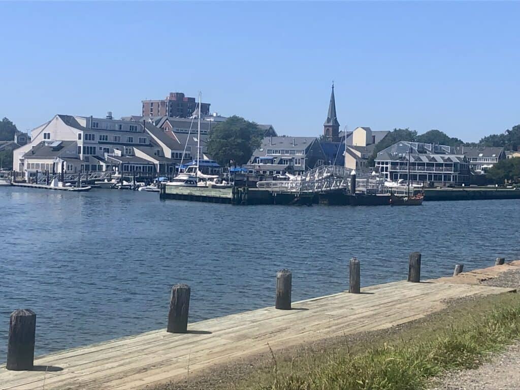 Harbor in Salem, with ships and boats on the water, and the town in the distance.