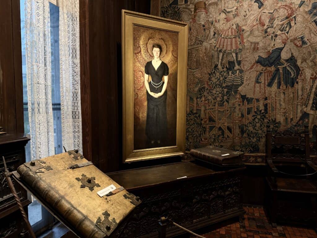 Portrait of Ms. Gardner in a low/cut long black dress with a tapestry in the background.